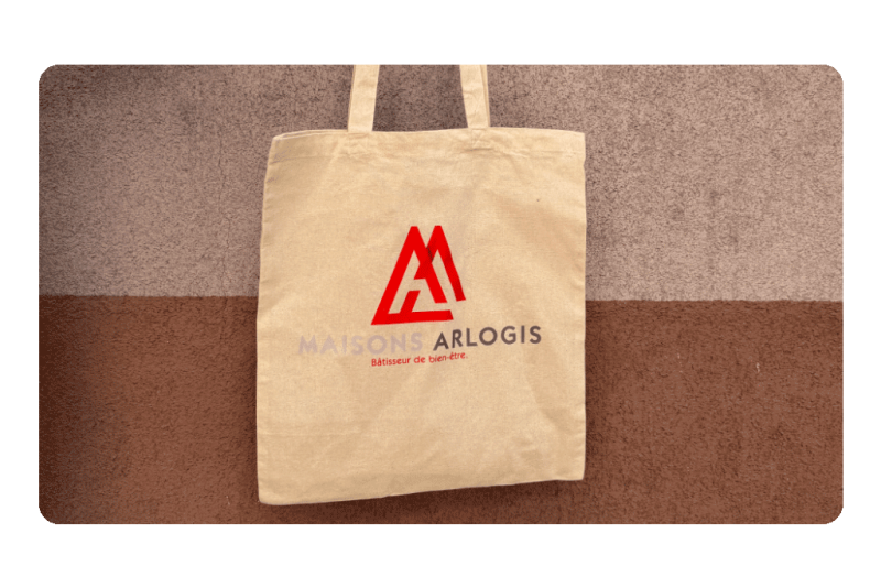 http://Totebag%20personnalisé%20Maisons%20Arlogis%20Alsace,%20présenté%20dans%20son%20intégralité,%20avec%20logo%20et%20couleurs%20de%20la%20marque%20visibles